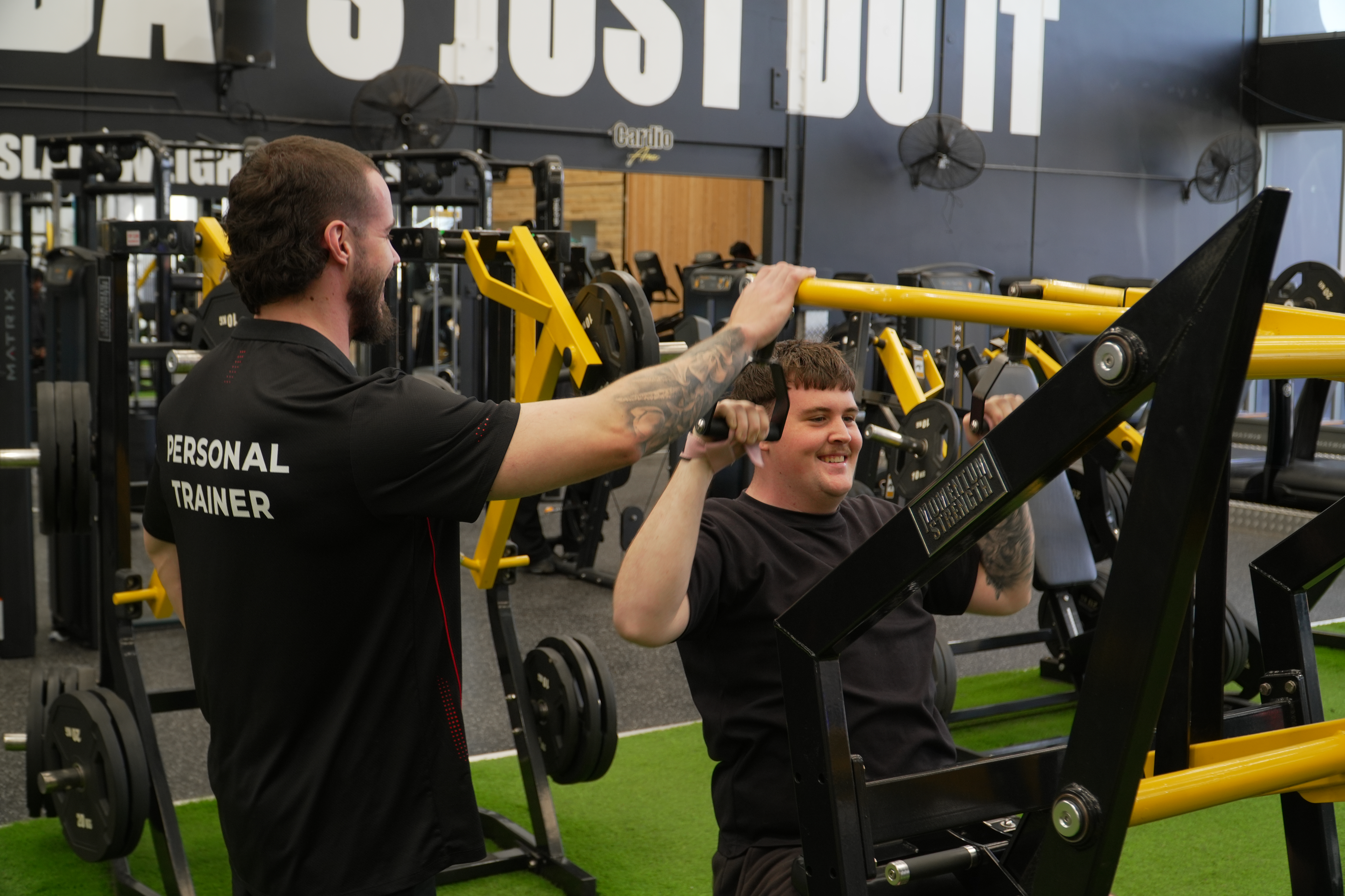 Braydon coaching a client on the lat pulldown machine